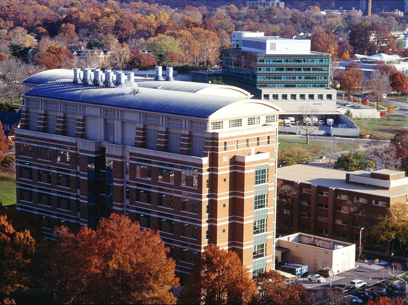 A view of the National Institutes of Health campus in Bethesda, Maryland, looking south beyond the Stokes Labs (Building 50) and Natcher Building (center) to the reflective façade of the National Library of Medicine (upper right). (Photo by National Institutes of Health)
