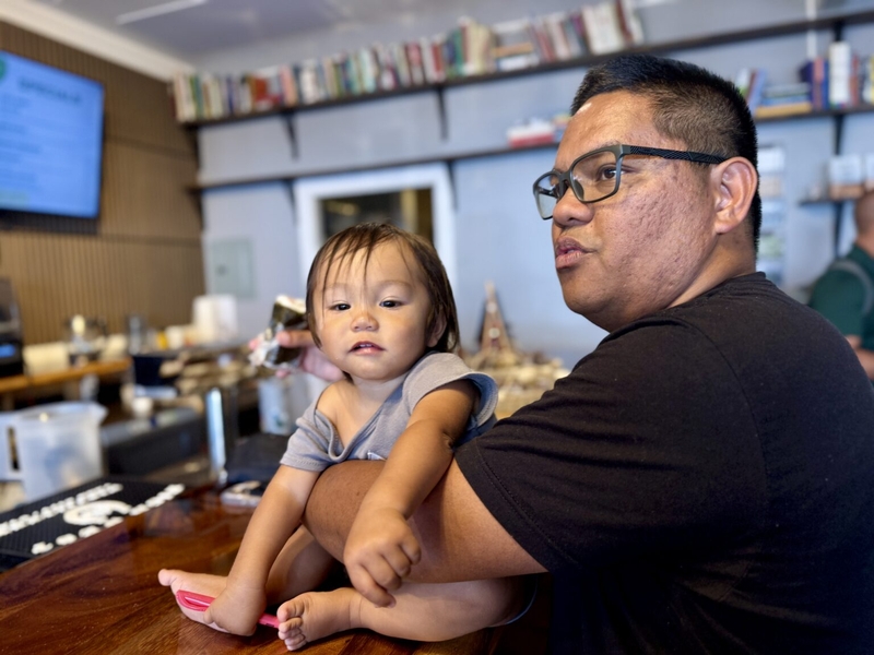 On a recent morning Kauaʻi County Councilman Addison Bulosan held a series of professional meetings at the coffee bar at Hale Līhuʻe, a nonprofit community center and coworking space, while wrangling his 13-month-old son Zenith. (Brittany Lyte/Civil Beat/2025)