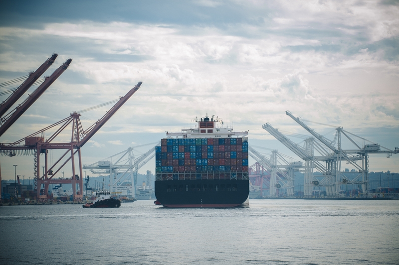 Tugboat and container ship in industrial harbor - stock photo