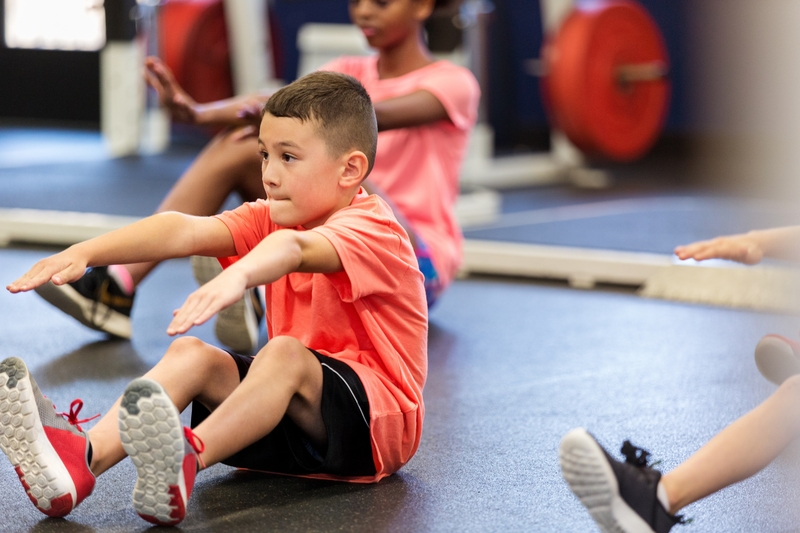 Elementary schoolboy concentrates while performing a sit-up during fitness class or PE class.