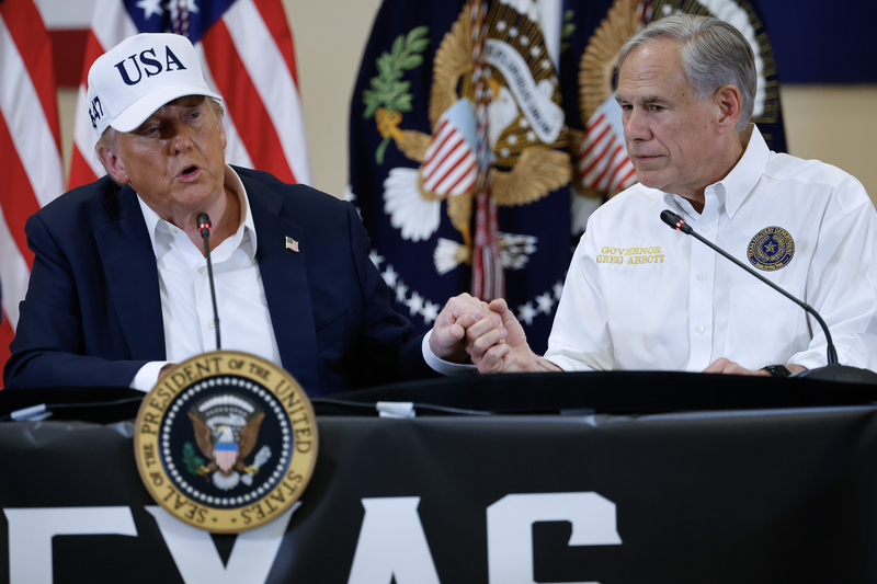 President Donald Trump and Texas Governor Greg Abbott hold hands during a round table event at the Hill Country Youth Event Center to discuss last week's flash flooding on July 11, 2025 in Kerrville, Texas. Trump traveled to Texas one week after flash flooding along the Guadalupe River swept through cities, mobile home parks and summer camps, killing 120 people. Ninety-six of those killed were in Kerr County, where the toll includes at least 36 children. (Photo by Chip Somodevilla/Getty Images)
