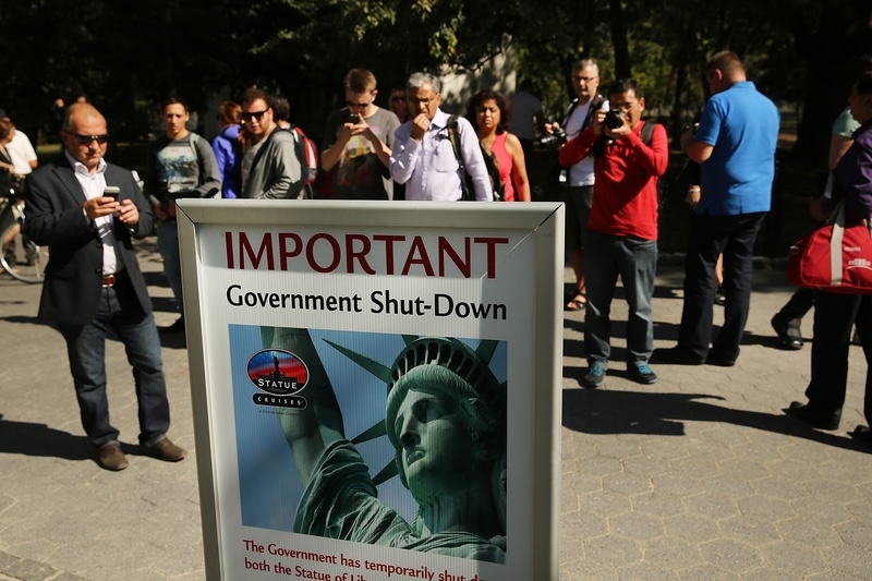 People in New York City look at a sign informing them that the Statue of Liberty is closed on Oct. 1, 2013, due to a government shutdown.  (Photo by Spencer Platt/Getty Images)