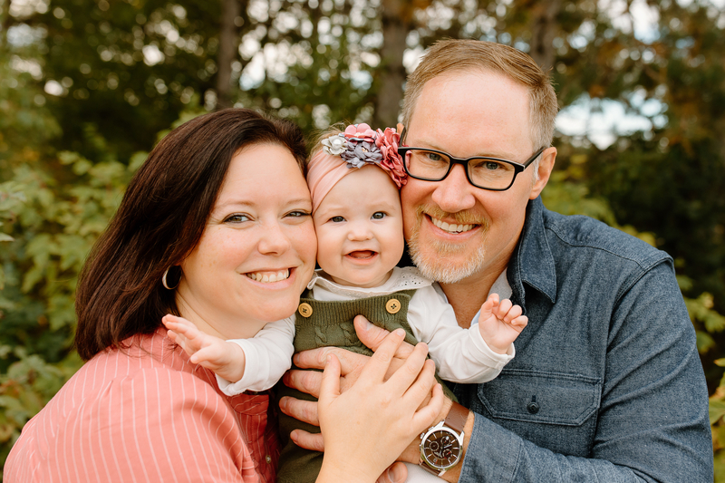 Parents who conceived through IVF hold their baby in a family portrait