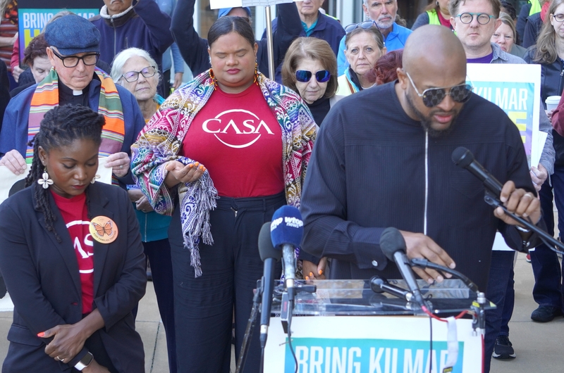 The Rev. Robert Turner, right, leads an opening prayer on Friday, Oct. 10, 2025, outside the U.S. District Court in Greenbelt, Maryland, in support of Kilmar Abrego Garcia, who had a hearing in court. Standing next to Turner is Ama Frimpong, an attorney with the immigrant advocacy group CASA. (Photo by William J. Ford/Maryland Matters)