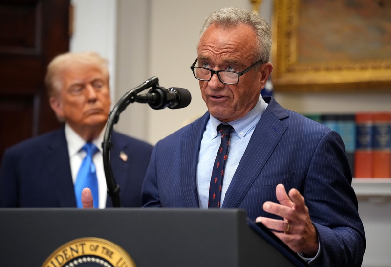 U.S. Health and Human Services Secretary Robert F. Kennedy Jr. speaks at a podium with President Donald Trump in the background