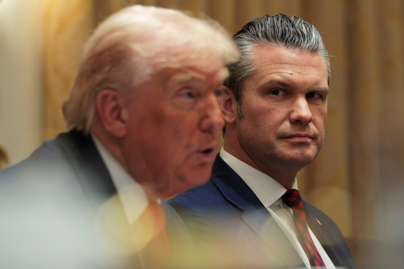 U.S. Secretary of Defense Pete Hegseth, right, looks on as U.S. President Donald Trump speaks during a meeting of his Cabinet in the Cabinet Room of the White House on Dec. 2, 2025 in Washington, D.C. (Photo by Chip Somodevilla/Getty Images)