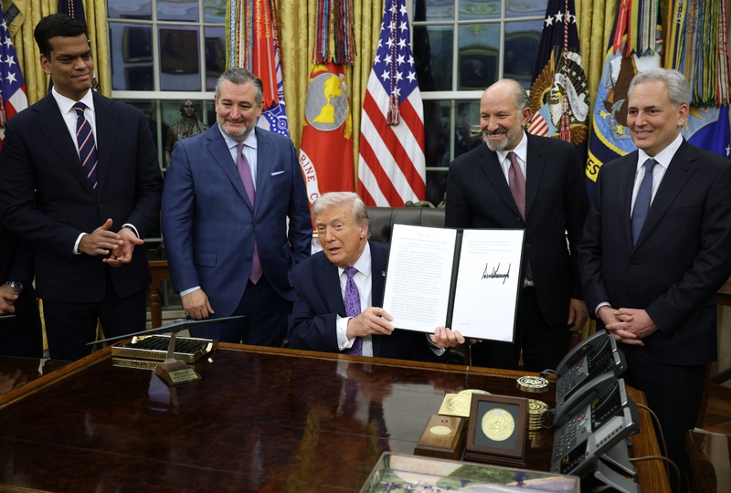 President Donald Trump displays a signed executive order as, left to right, Sen. Ted Cruz, R-Texas, Commerce Secretary Howard Lutnick and White House artificial intelligence and crypto czar David Sacks look on in the Oval Office of the White House on Dec. 11, 2025 in Washington, D.C. (Photo by Alex Wong/Getty Images)