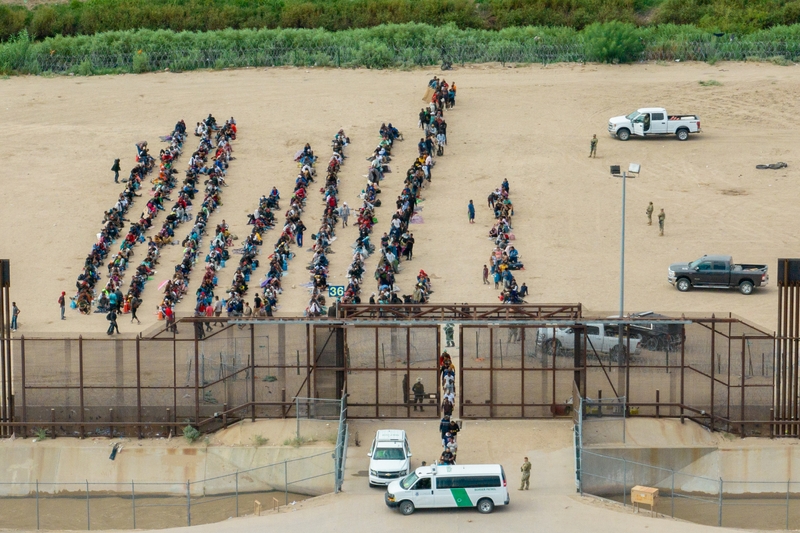 In an aerial view, migrants are seen grouped together while waiting to be processed on the Ciudad Juarez side of the border on September 21, 2023 in El Paso, Texas. A recent surge of migrant crossings have occurred along the Southwestern region of the United States border. (Photo by Brandon Bell/Getty Images)