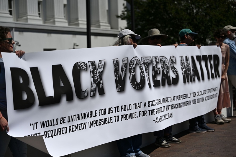 A group of protestors hold a banner saying “Black Voters Matter” with a quote from Allen v. Milligan, a 2023 case that required Alabama to draw a second congressional district to give Black voters an opportunity to elect their preferred leaders, on May 4, 2026 at the Alabama Statehouse in Montgomery, Alabama. (Photo by Brian Lyman/Alabama Reflector)