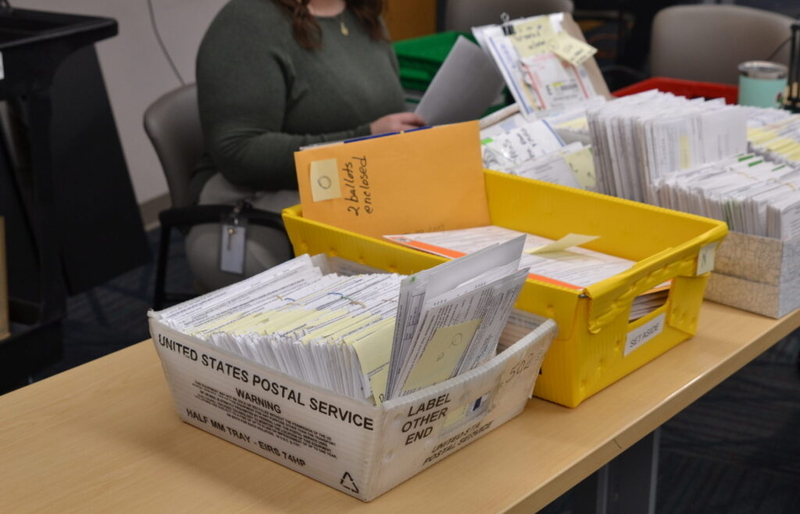 Ballots that had arrived by mail or were set aside on Election Day sit on a table at the Cass County Courthouse on Nov. 18, 2024, waiting to be reviewed. (Photo by Jeff Beach/North Dakota Monitor)