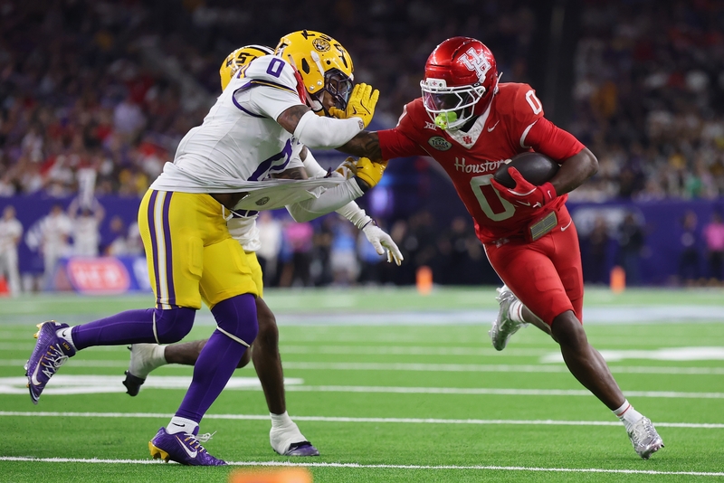 Amare Thomas #0 of the Houston Cougars gives a stiff arm to Tamarcus Cooley #0 of the Louisiana State Tigers in the second half during the Kinder's Texas Bowl at NRG Stadium on December 27, 2025 in Houston, Texas. (Photo by Tim Warner/Getty Images)