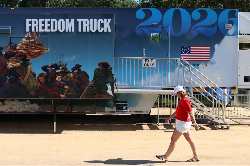 a woman in red walks by a trailer that says 