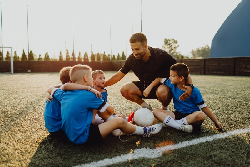 Youth sports coach with children on soccer field huddling before the final tournament match - stock photo