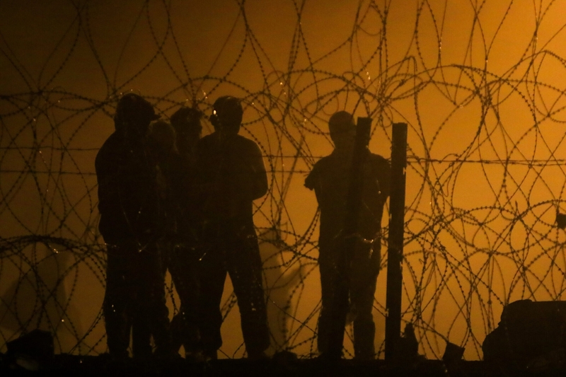 Migrants wait through the night on May 10, 2023, in a dust storm, on land between the Rio Grande and the U.S.-Mexico border wall, hoping they will be processed by immigration authorities before the expiration of Title 42, a public health order used to expel migrants. (Photo by Corrie Boudreaux/Source NM)