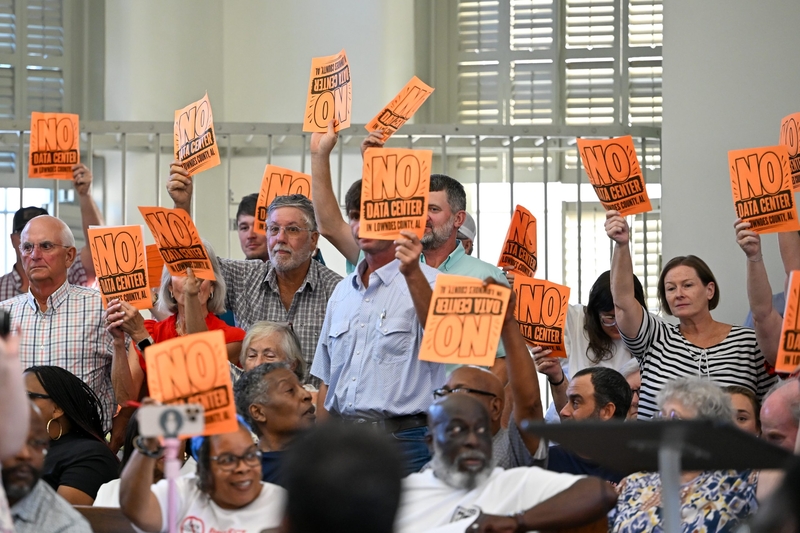 Alabamans hold up signs that read “No Data Center” at a County Commission meeting on Aug. 24, 2026, in Hayneville, Alabama, in the Lowndes County Courthouse. (Anna Barrett/Alabama Reflector)