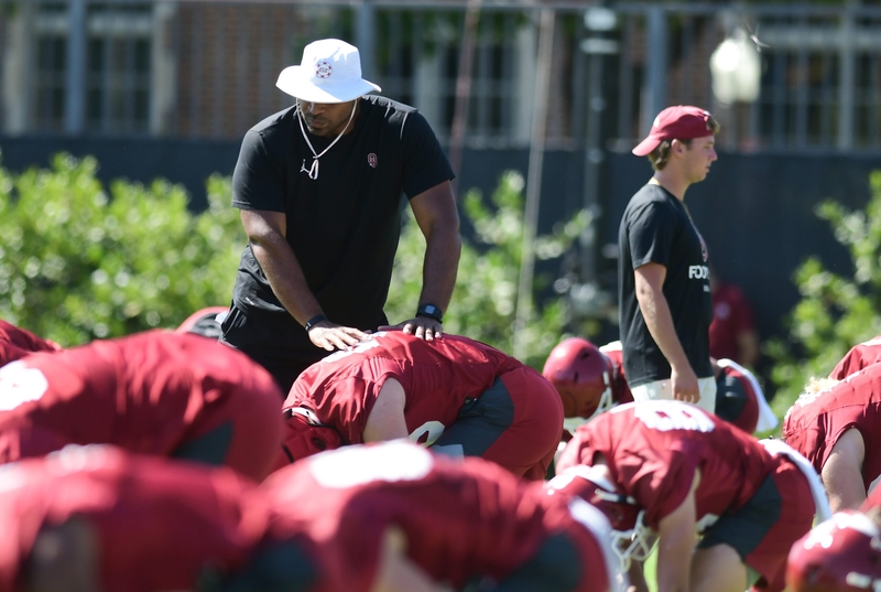 University of Oklahoma football coach helps players stretch during practice on Aug. 4, 2023. (Photo by Kyle Phillips/For Oklahoma Voice)