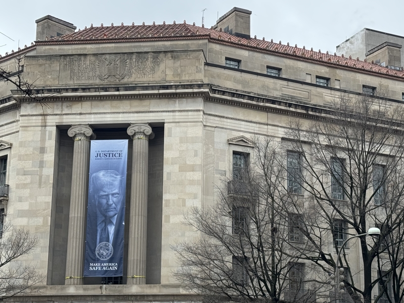 A banner showing President Donald Trump hangs on the Department of Justice on Feb. 20, 2026. (Photo by Shauneen Miranda/States Newsroom)