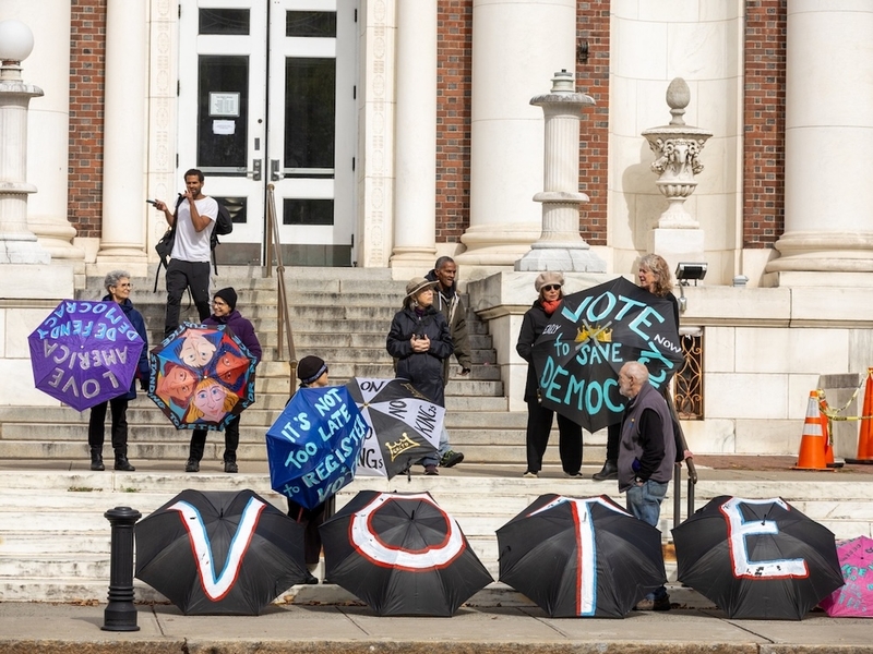 Members of the Umbrella Brigade stand outside the New Haven Free Public Library in New Haven Connecticut, during a No Kings: Vote Early rally at New Haven Green on Saturday, Oct. 17, 2026. (Photo by Sarah Gordon/CT Mirror)