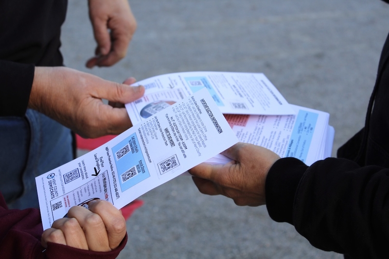 Volunteers hand out flyers with voting information at the No Kings event in downtown Grand Rapids, Michigan, on Oct. 17, 2026. (Photo by Emma J Nelson/Michigan Advance)