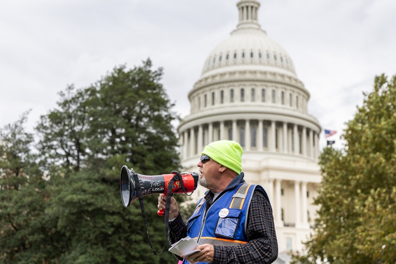 Umbrella Walk organizer Peter Stinson speaks to protesters as the walk ends at the U.S. Capitol West Lawn in Washington, D.C., on Oct. 17, 2026. (Photo by Baya Burgess/States Newsroom)