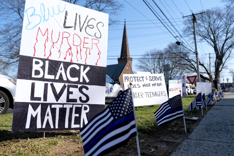 Flags and signs in solidarity with either State Trooper Brian North or Mubarak Soulemane lined the front of the Milford Courthouse on March 13, 2024. CREDIT: SHAHRZAD RASEKH / CT MIRROR