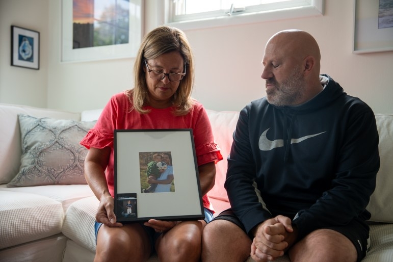 Tracy and Jason Ciccone hold a portrait of their son, Tyler Cole, and Tyler’s son, Brantley, in their home in Danbury on Aug. 18, 2025. Cole died from an overdose last year while in custody at Garner Correctional Institution in Newton. Credit: Dana Edwards / CT Mirror