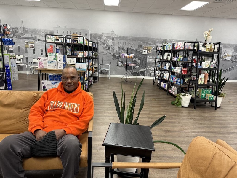A man sits at a pharmacy.