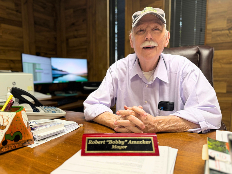 A man sits behind his desk.