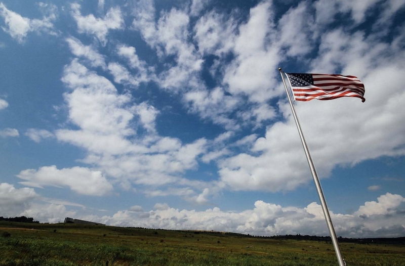 The American flag flies at the entry to the pathway that leads to the Wall of Names at the Flight 93 National Memorial in Stonycreek Township, Pennsylvania. The visitor center is in the background. (Photo courtesy of Tim Lambert)