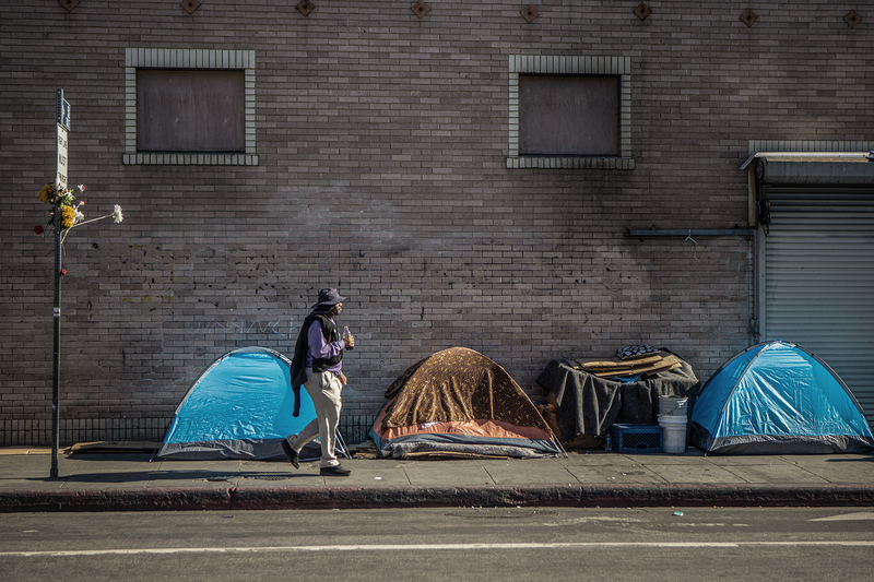 A person walks by a homeless encampment in downtown Los Angeles on Nov. 18, 2022. Photo by Larry Valenzuela for CalMatters/CatchLight Local