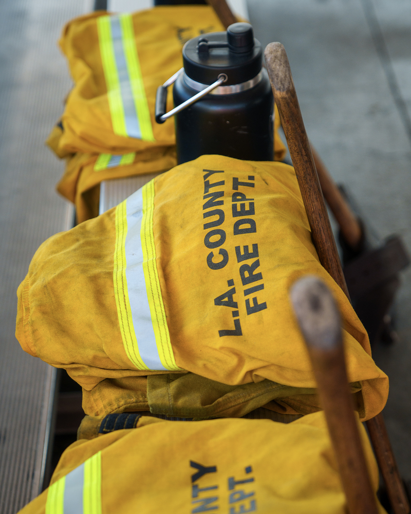 Bright yellow firefighter training jackets and gear are laid out on a bench .