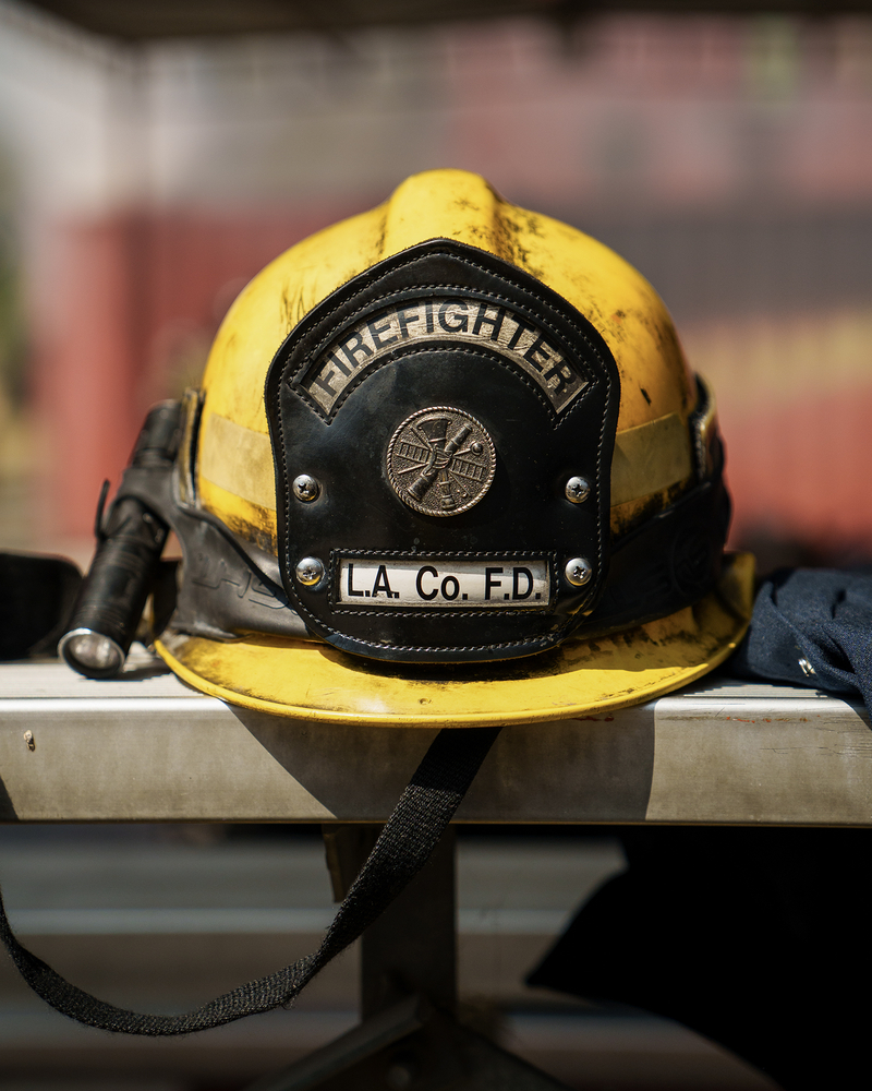 A bright yellow firefighter's helmet sits on a bench.