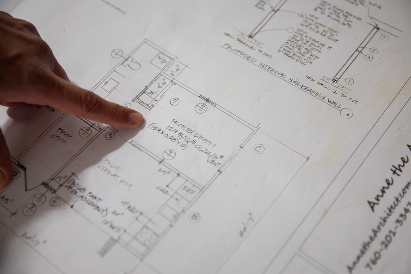 A close up view of a person's index finger pointing at the drawn floor plans of a garage under construction.