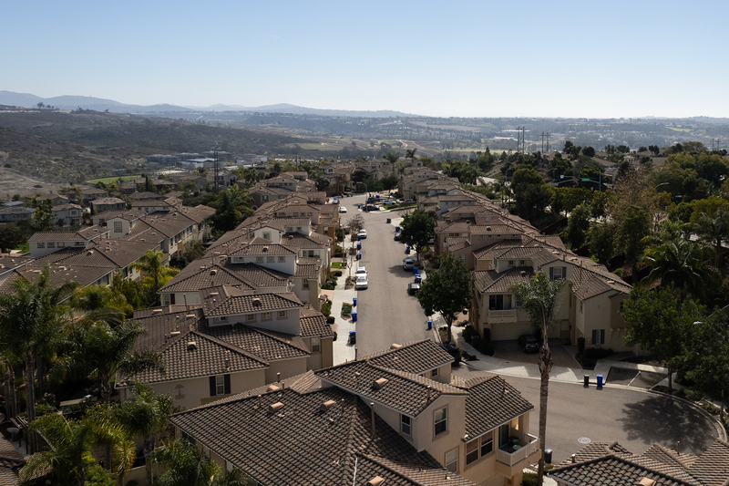 An aerial view of a cul-de-sac with beige and brown homes lined on either side of the street.