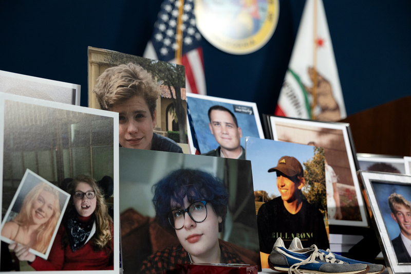 Several printed photographs of people are displayed upright on a table, with flags and a state seal visible in the background.