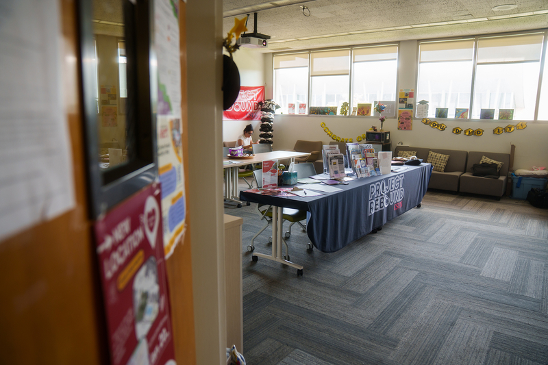 A view inside a study room with a table with a blue tablecloth that reads “Project Rebound” while light is pouring in from a window behind it.