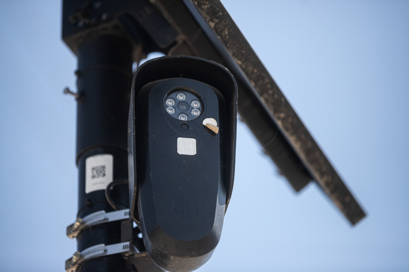 A small black camera is attached to a pole.