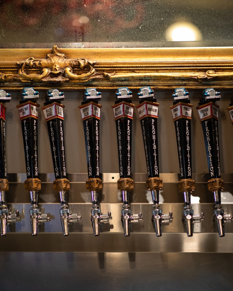 Black draft beer handles line the wall of a bar.