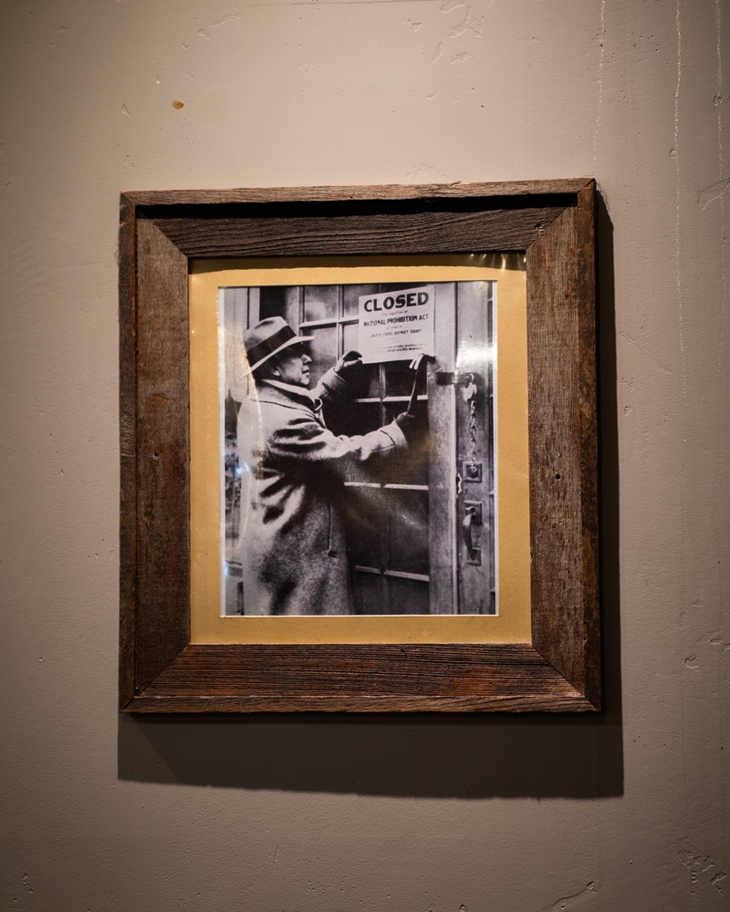 A framed historical photos of a person nailing a sign that signs "closes" onto a door.