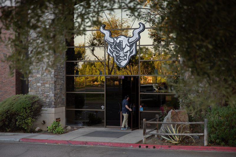 A person enters a fully tinted building with a large garghoul logo at the top.