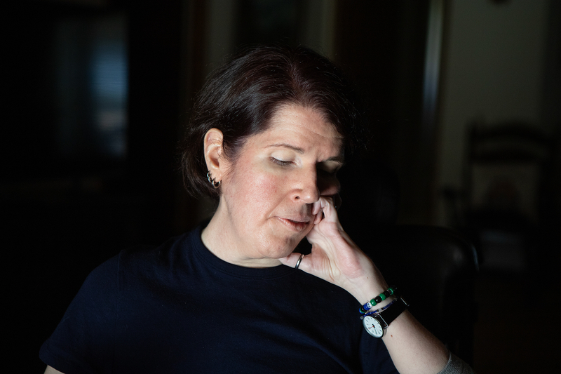 A person with disabilities looks down with their left hand sitting near their cheek while they do circulation exercises.