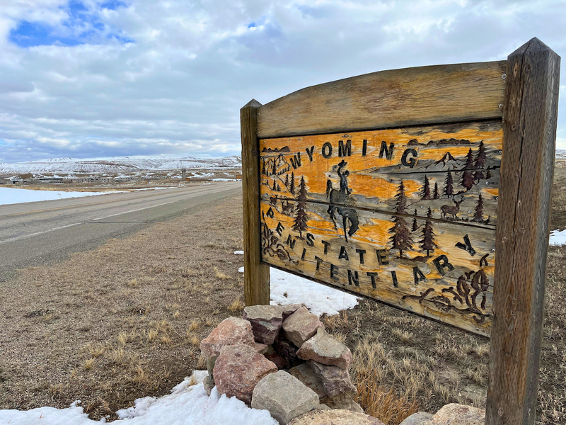 A a faded sign with cracking paint that says Wyoming State Penitentiary