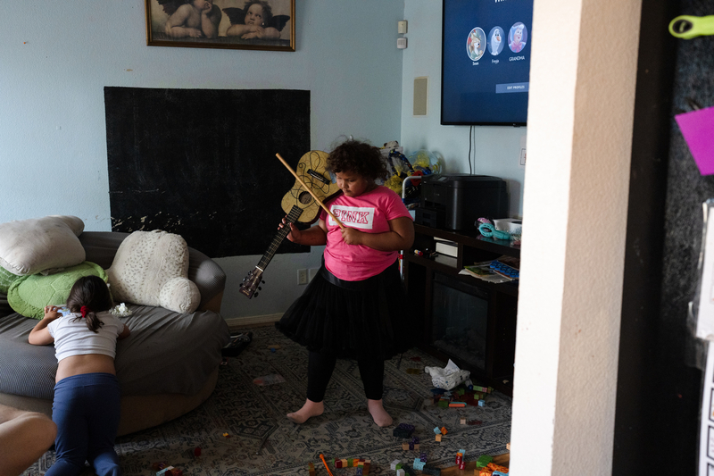Seven-year-old Freyja Radtke, who suffers from Bardet-Biedl syndrome, a condition which causes excessive weight gain and hormonal imbalances, and in her particular case, an inability to control her own appetite, pretends to play the violin with a guitar at the family’s home on Saturday, February 28, 2026 in El Paso, Texas. Because Freyja is due for a medical test next week, she is forced to be off of Imcivree, the medication that controls her hormonal imbalances that lead to excessive hunger, until after