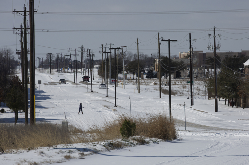 A pedestrian crosses snow-covered streets in McKinney during Winter Storm Uri on Feb. 15, 2021.