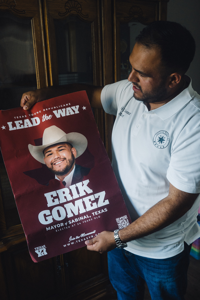 Gomez holds a poster from his mayoral campaign.