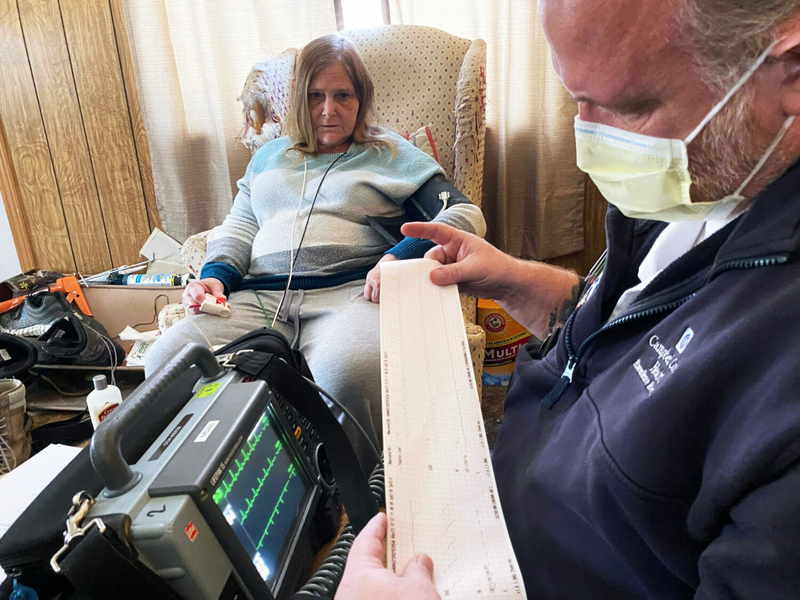 Community paramedic Jason Frye reads electrocardiogram results for Sandra Lane during a home visit in Gillette, Wyoming. The test measures electrical signals in the heart. (Arielle Zionts/KFF Health News)