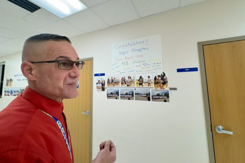 Principal Brian Brown walks the halls on Dec. 17, 2025, and discusses a sign that celebrates Norris Elementary's attendance rate. He also prints and posts photos around the school to acknowledge students who have done well in sports, academics and extracurricular activities. (Photo by Meghan O'Brien/South Dakota Searchlight)