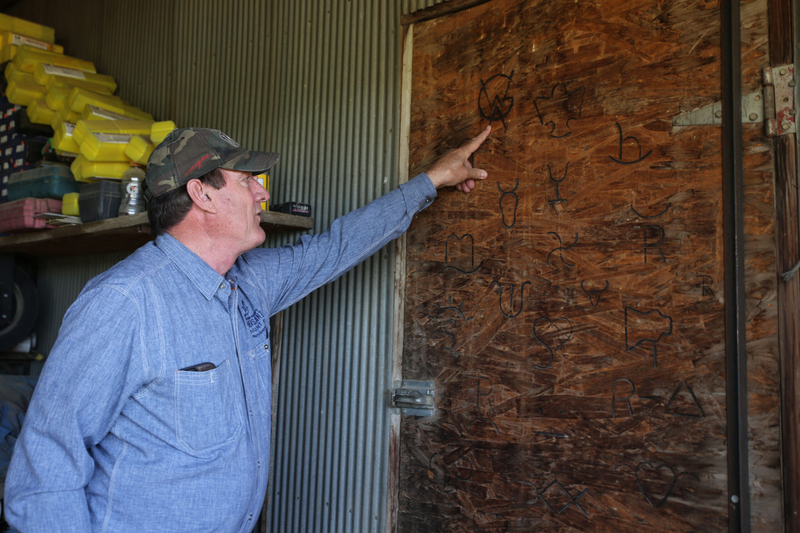 South Dakota Gov. Larry Rhoden points to an example of a brand he made in his welding shop on his ranch in Union Center, South Dakota on June 26, 2026. Rhoden owns a custom branding business out of the hobby. (Photo by Makenzie Huber/South Dakota Searchlight)