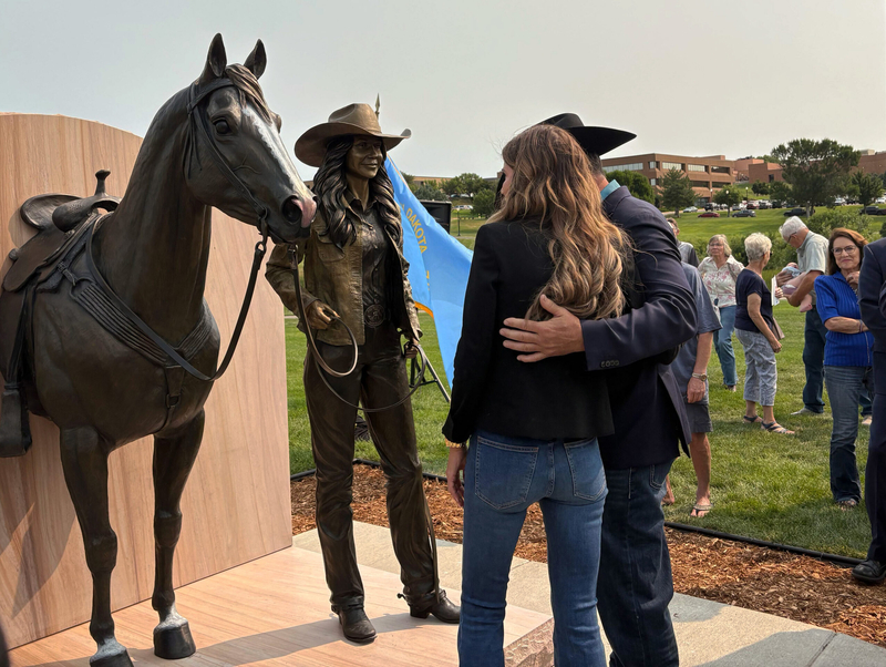 At an event on Aug. 7, 2026, in Pierre, former Gov. Kristi Noem and artist John Lopez get a closer look at his statue of Noem leading her horse, the latest addition to the South Dakota Trail of Governors. (Photo by Meghan O'Brien/South Dakota Searchlight)