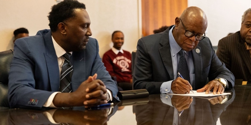 Imola Automotive USA CEO Rodney Henry, left, looks on as Dr. Isaac Crumbly, of Fort Valley State University in Georgia, signs an agreement in 2024 to collaborate on science and technology development, part of Imola’s plan to develop an electric vehicle plant in Fort Valley. Since then, however, there has been no sign of construction.